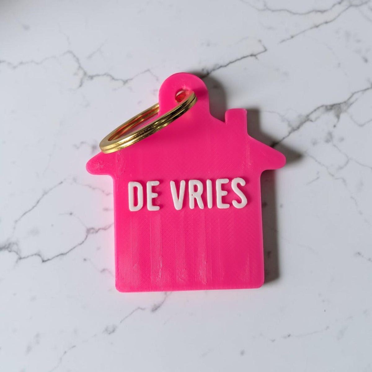 Roze sleutelhanger huisje met achternaam De Vries en gouden sleutelring