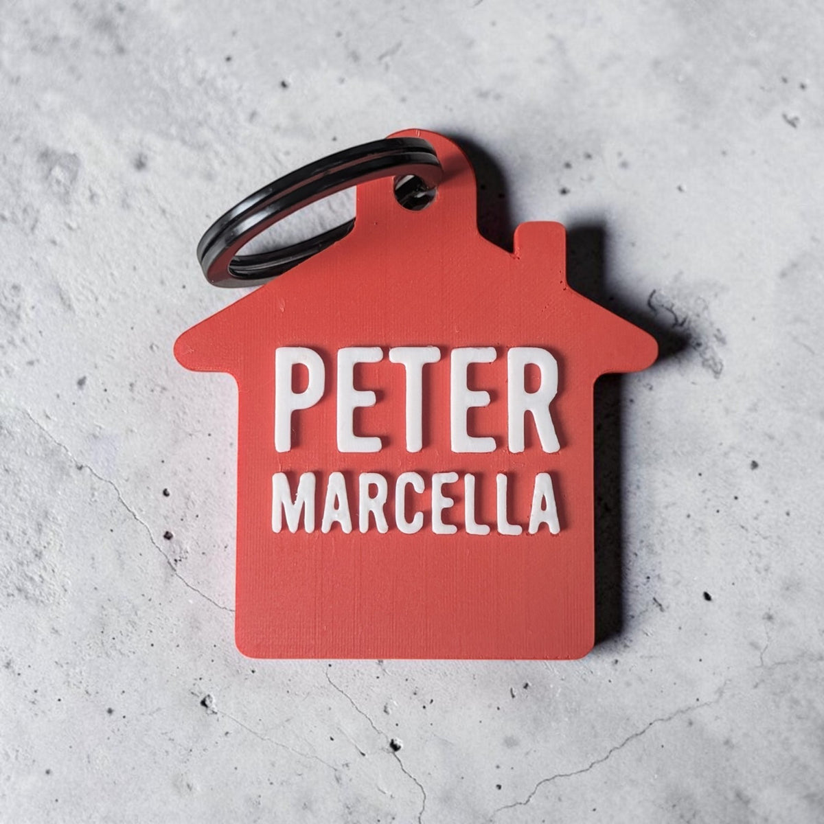 Rode sleutelhanger huisje met twee namen, Peter en Marcella, als cadeau voor samenwonen