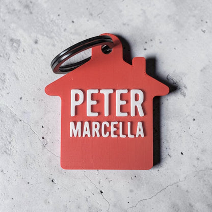 Rode sleutelhanger huisje met twee namen, Peter en Marcella, als cadeau voor samenwonen
